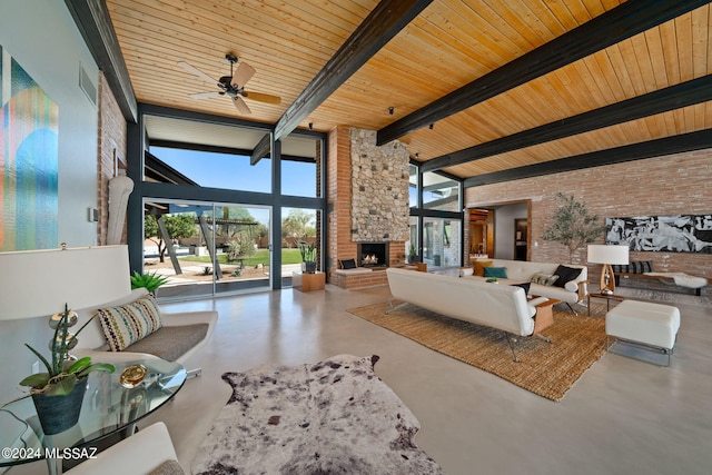 living area featuring beam ceiling, a fireplace, a high ceiling, finished concrete floors, and brick wall