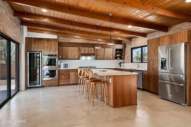 kitchen featuring brown cabinetry, a kitchen island, decorative light fixtures, stainless steel appliances, and light countertops