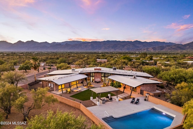 pool at dusk with a mountain view and a patio