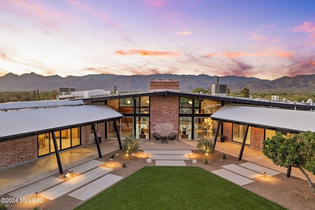 back house at dusk featuring a patio area and a mountain view