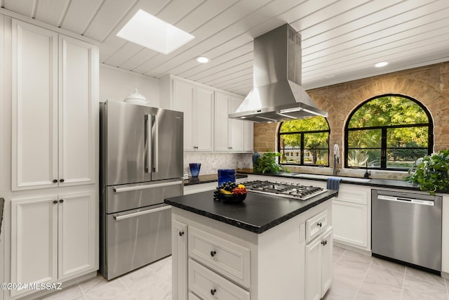 kitchen with a skylight, a center island, stainless steel appliances, island range hood, and white cabinets