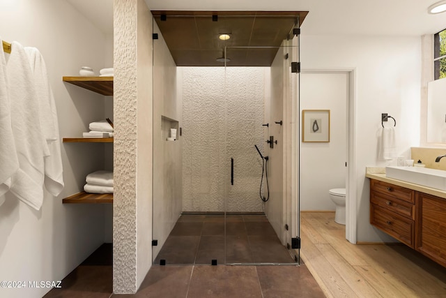 bathroom featuring vanity, hardwood / wood-style flooring, toilet, and walk in shower