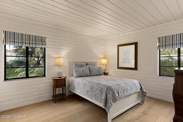 bedroom featuring hardwood / wood-style flooring, wood ceiling, and brick wall