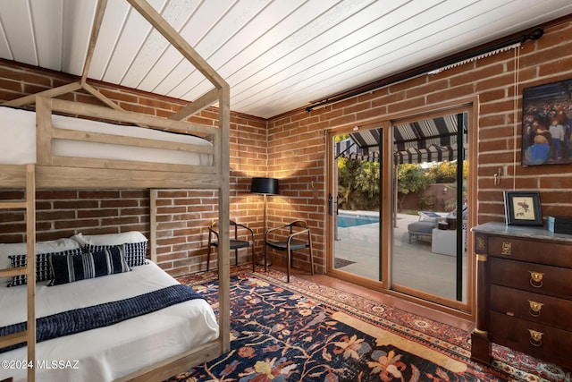 bedroom featuring access to exterior and brick wall