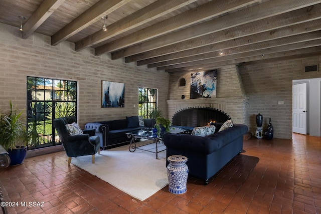 living room featuring beam ceiling, a fireplace, and brick wall