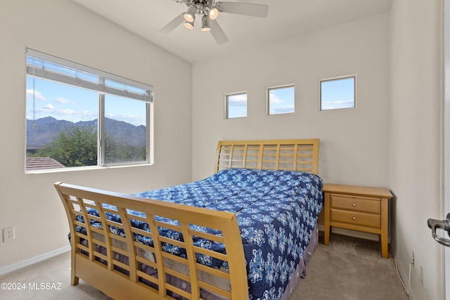 carpeted bedroom featuring a mountain view, baseboards, and a ceiling fan