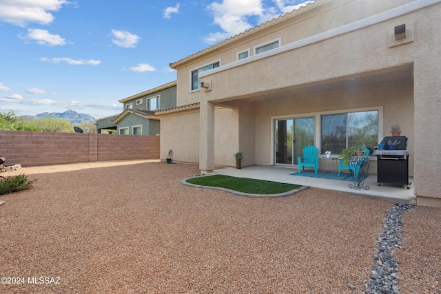 back of house featuring a mountain view, a patio area, fence, and stucco siding