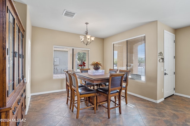 dining space with dark tile patterned floors and a chandelier