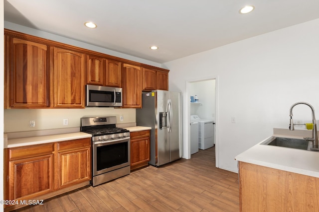 kitchen featuring light wood-type flooring, washing machine and dryer, stainless steel appliances, and sink