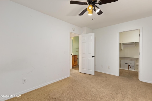 unfurnished bedroom with a walk in closet, ceiling fan, and light carpet