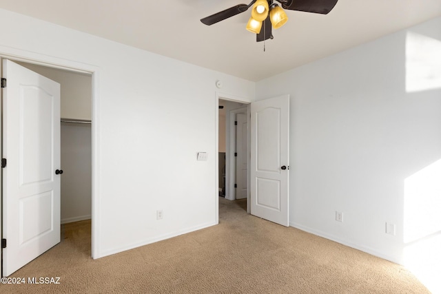 unfurnished bedroom with ceiling fan, light colored carpet, a spacious closet, and a closet