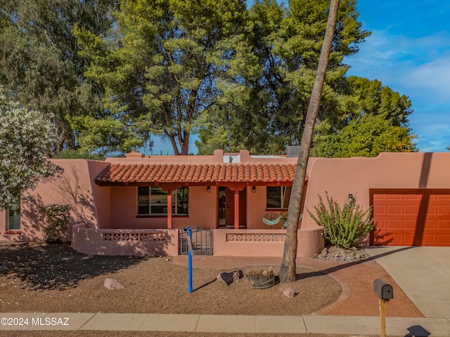 pueblo revival-style home with a porch and a garage