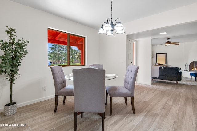 dining space with light hardwood / wood-style flooring and ceiling fan with notable chandelier