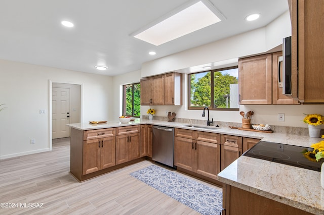 kitchen with light hardwood / wood-style flooring, kitchen peninsula, stainless steel appliances, and sink