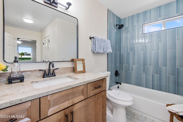 full bathroom with vanity, tiled shower / bath combo, toilet, and ceiling fan