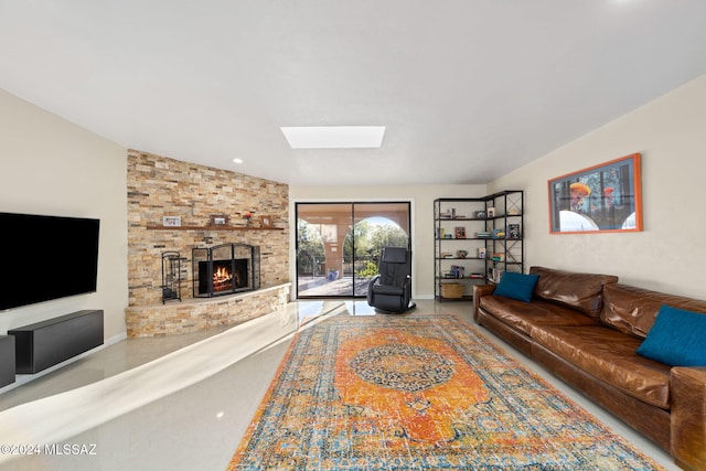 living room featuring a stone fireplace and vaulted ceiling with skylight