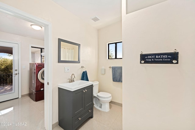 bathroom featuring tile patterned flooring, vanity, washer and dryer, and toilet