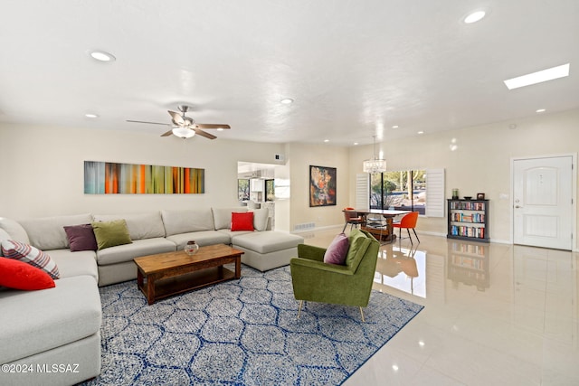 tiled living room with ceiling fan with notable chandelier