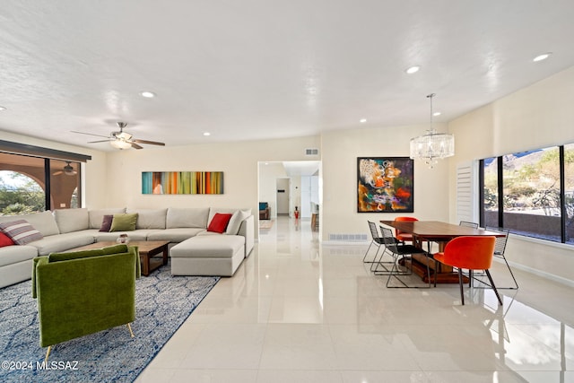 tiled living room with ceiling fan with notable chandelier