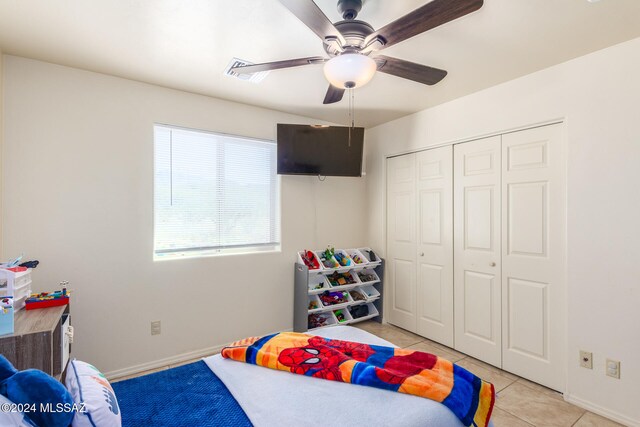 bedroom featuring light tile patterned floors, ceiling fan, and a closet