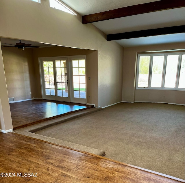 unfurnished room featuring a wealth of natural light, lofted ceiling with beams, and wood-type flooring