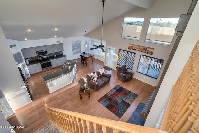 living room featuring ceiling fan, wood-type flooring, sink, and high vaulted ceiling