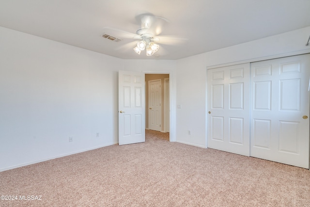 unfurnished bedroom featuring ceiling fan, light colored carpet, and a closet