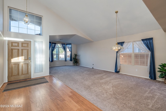 entryway featuring hardwood / wood-style floors, a healthy amount of sunlight, high vaulted ceiling, and a chandelier