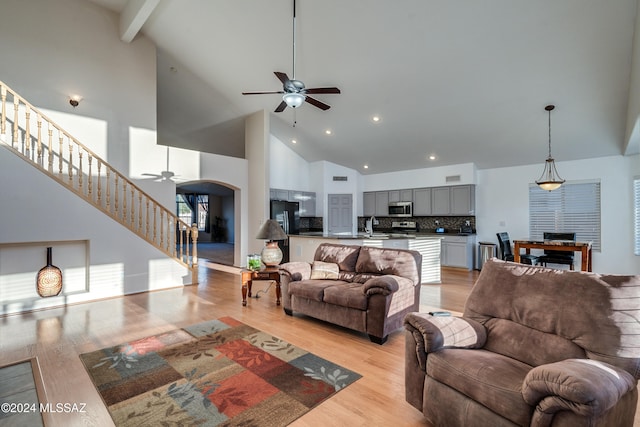 living room featuring ceiling fan, high vaulted ceiling, and light hardwood / wood-style floors