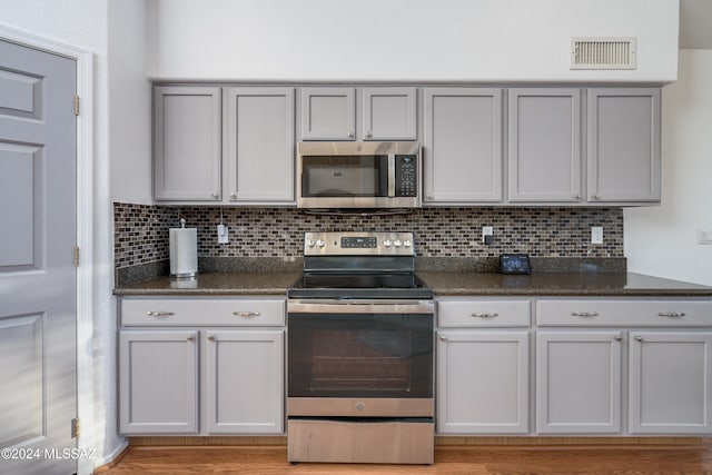 kitchen with decorative backsplash, appliances with stainless steel finishes, and light hardwood / wood-style flooring