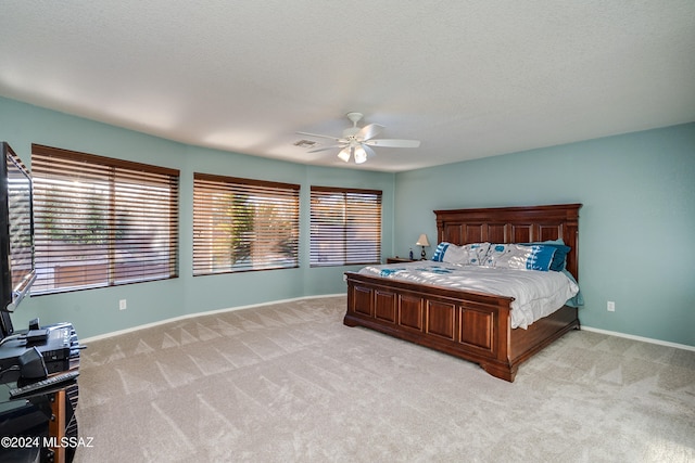 bedroom featuring light carpet, a textured ceiling, and ceiling fan