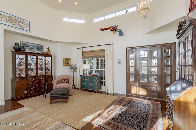 sitting room with a towering ceiling, dark wood-type flooring, and a notable chandelier