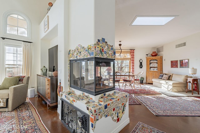 living room featuring a high ceiling, a healthy amount of sunlight, and a skylight