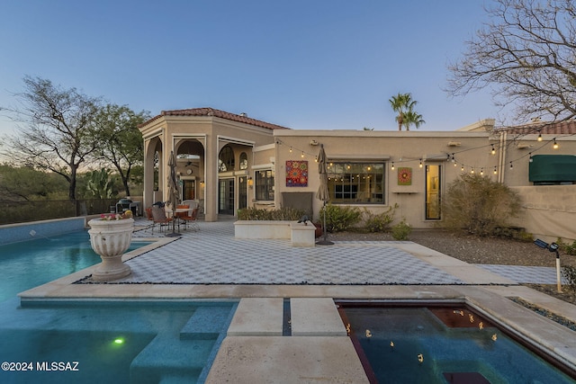 pool at dusk featuring a patio