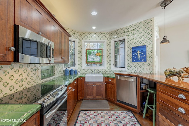 kitchen featuring sink, tile counters, pendant lighting, stainless steel appliances, and backsplash