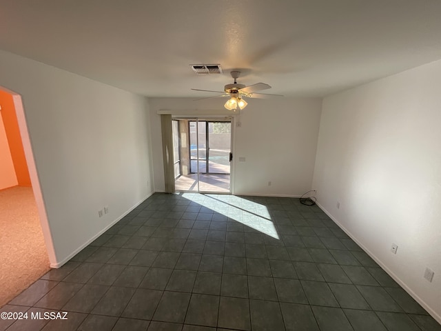 unfurnished room featuring dark tile patterned floors and ceiling fan