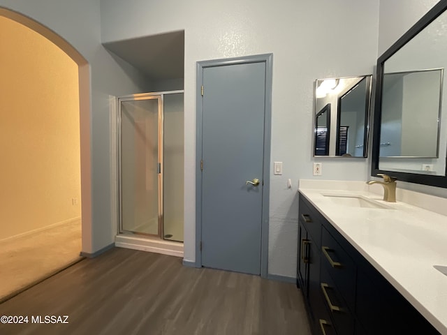 bathroom featuring wood-type flooring, a shower with door, and vanity