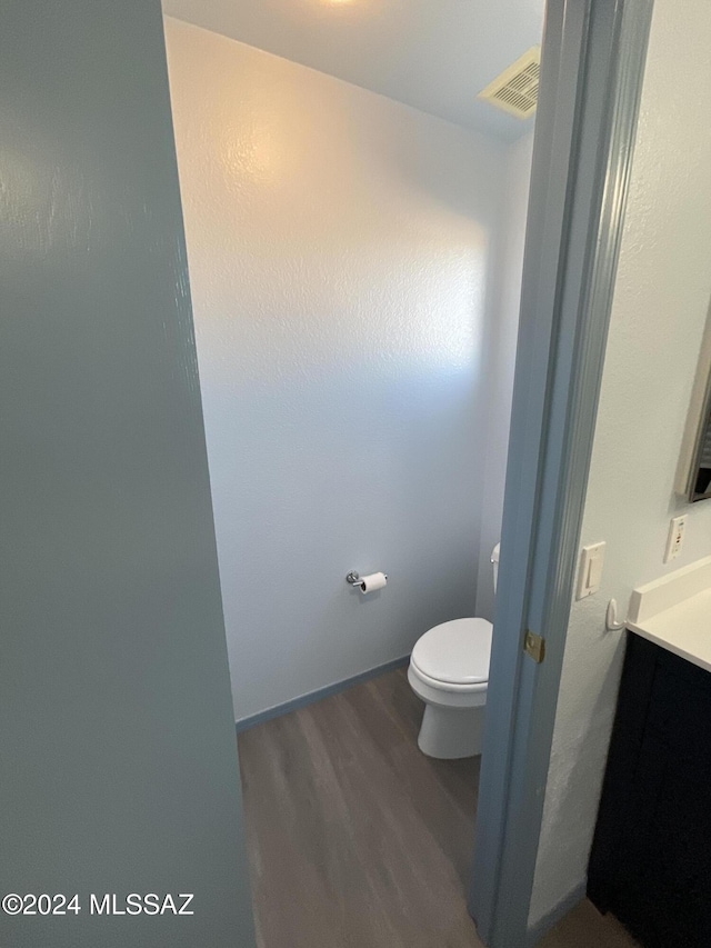 bathroom with wood-type flooring, toilet, and vanity