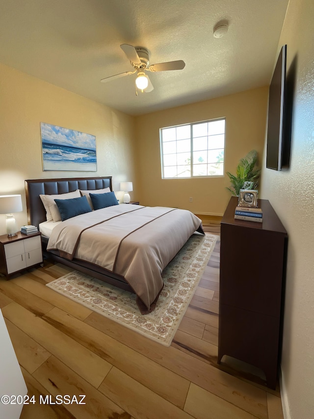 bedroom featuring wood-type flooring, ceiling fan, and a textured ceiling