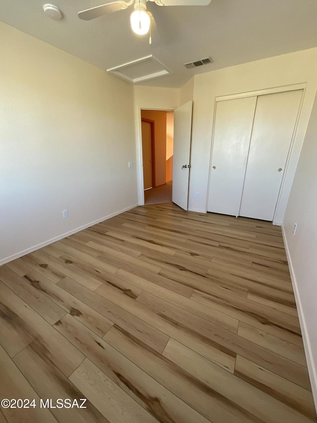 unfurnished bedroom featuring ceiling fan, light hardwood / wood-style floors, and a closet