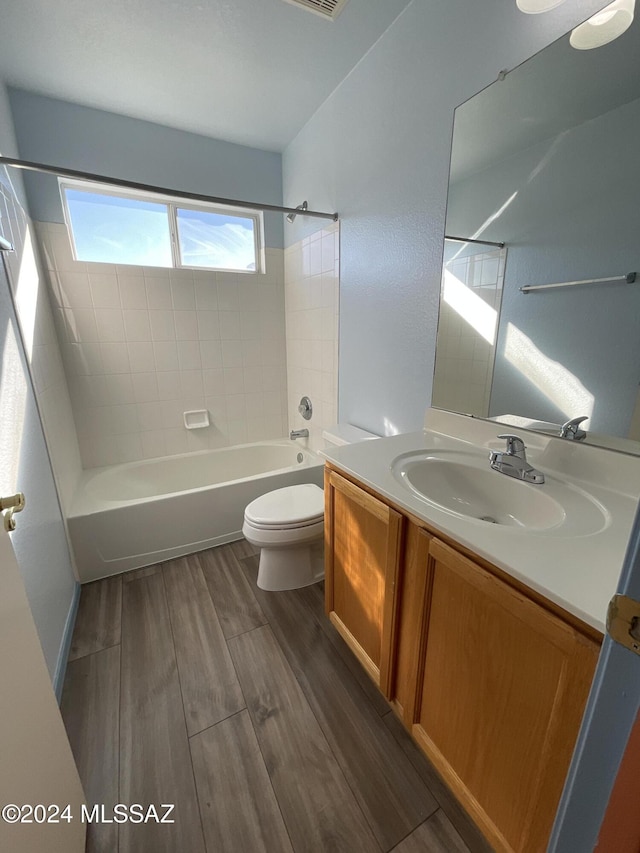 full bathroom featuring vanity, tiled shower / bath combo, wood-type flooring, and toilet