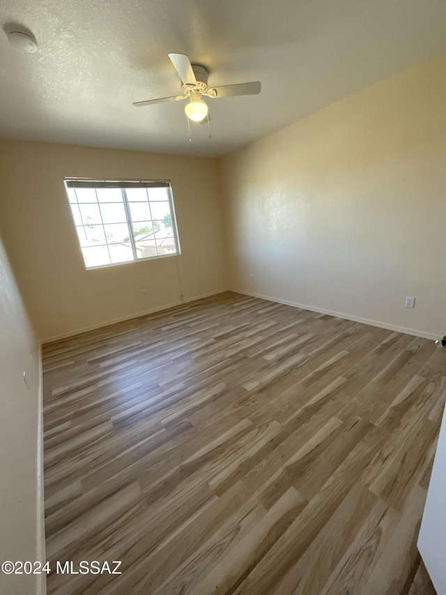 unfurnished room featuring wood-type flooring, a textured ceiling, and ceiling fan