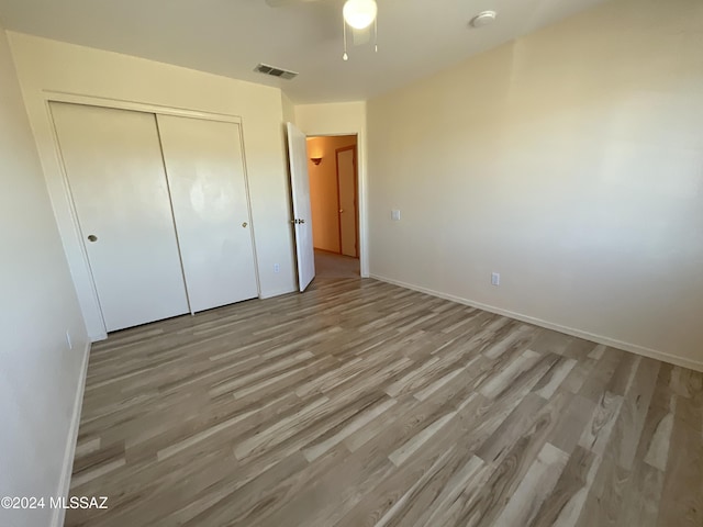 unfurnished bedroom featuring light hardwood / wood-style flooring, a closet, and ceiling fan