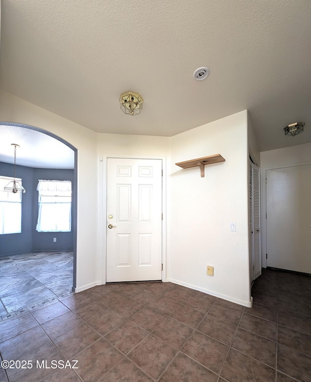 2655 W Desert Brook Ct, Tucson, AZ 85742 - entryway featuring dark tile patterned flooring, baseboards, arched walkways, and a textured ceiling