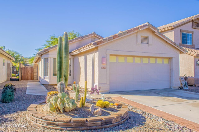 mediterranean / spanish house featuring a garage, fence, concrete driveway, a tiled roof, and stucco siding