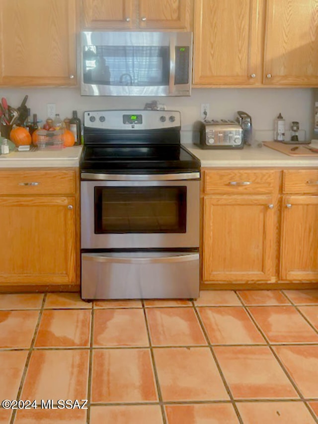 kitchen with light tile patterned flooring and appliances with stainless steel finishes