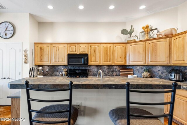 kitchen with black appliances, a breakfast bar, sink, and tasteful backsplash