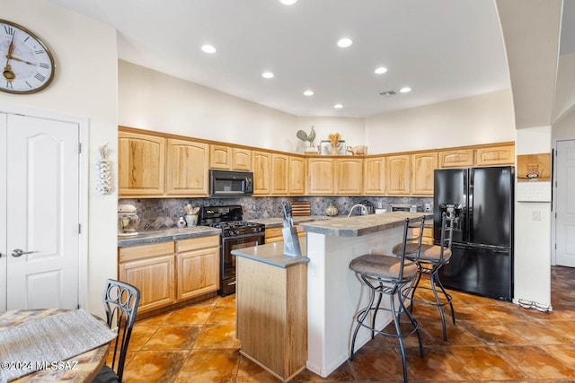 kitchen featuring a center island, light brown cabinets, black appliances, a kitchen breakfast bar, and decorative backsplash