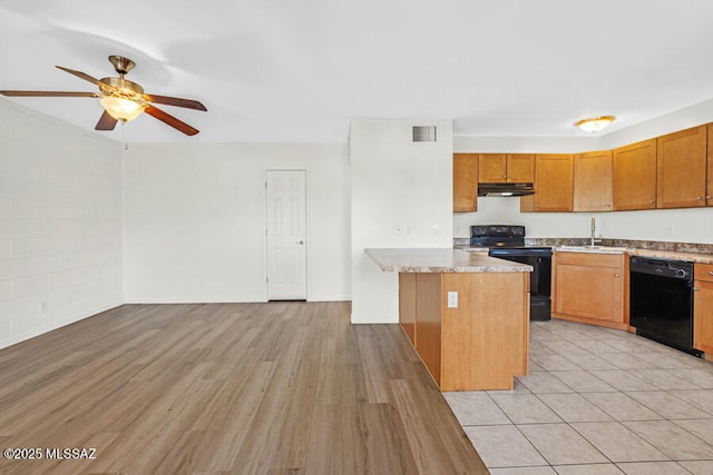 kitchen with a sink, a kitchen island, visible vents, brown cabinets, and black appliances