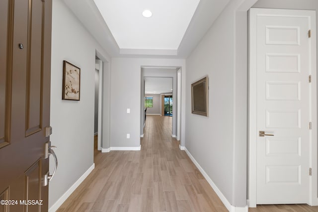 hallway featuring a raised ceiling and light hardwood / wood-style floors